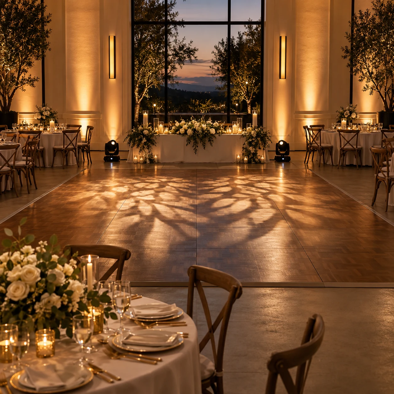 Elegant wedding reception with warm amber uplighting and patterned light across the dance floor.